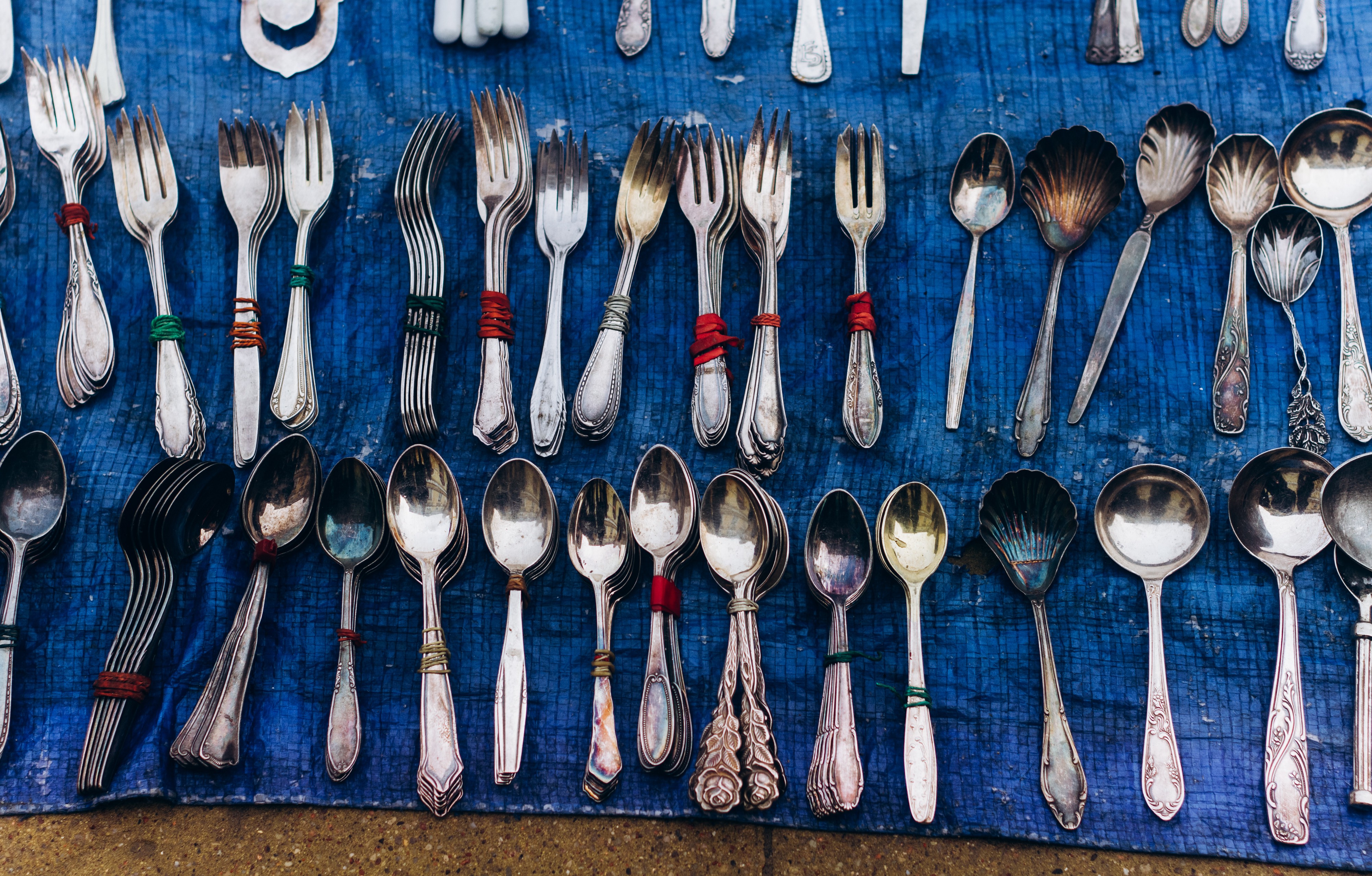 Grouped rows of forks and spoons, with identical items stacked and held together with rubber bands